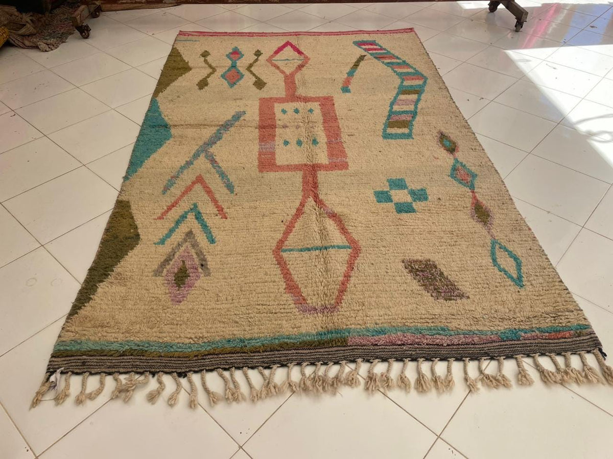 Front view of a vintage Moroccan rug showcasing tribal designs in beige, red, blue, and green.