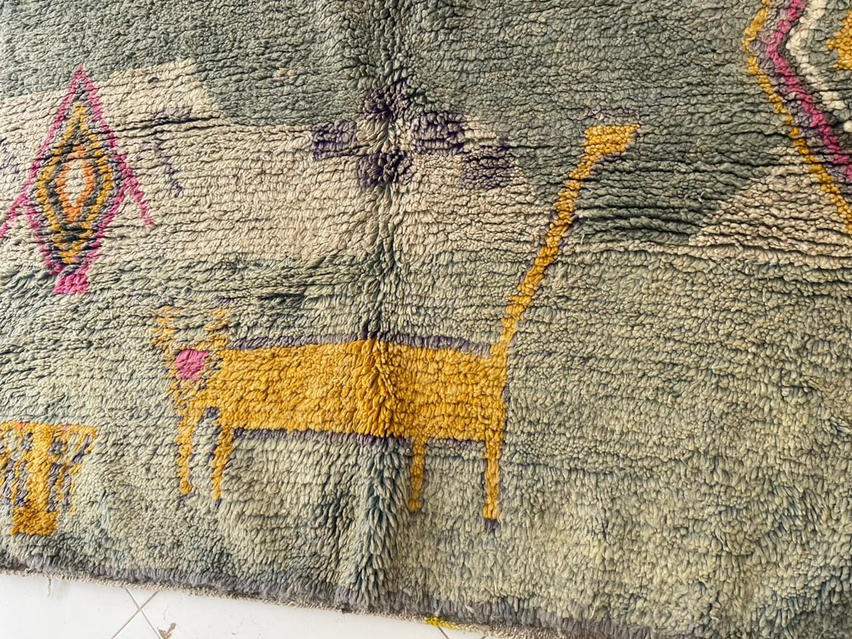 Close-up detail of a vintage Moroccan rug with animal motifs in green, yellow, and purple.
