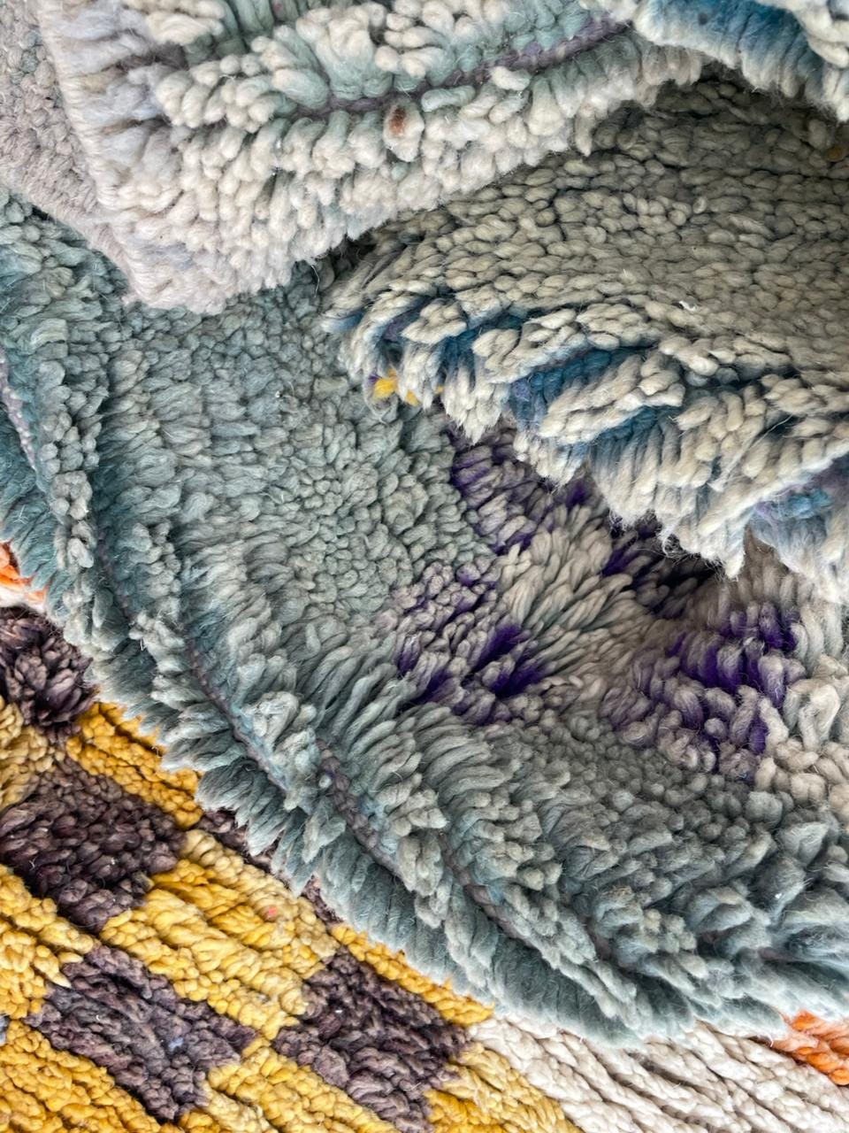Close-up detail of a vintage Moroccan rug displaying circular patterns in blue, green, yellow, and purple.