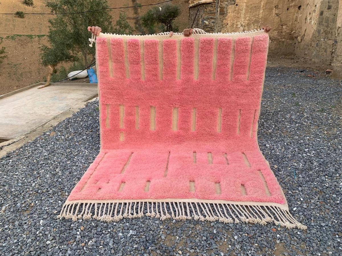 Lifestyle shot of a pink Moroccan rug with fringe edges in a natural setting.
