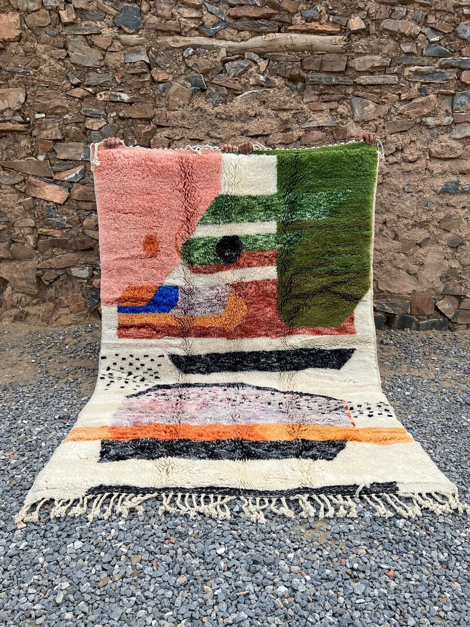 Lifestyle image of a pink colorful Moroccan rug with fringed edges and vibrant geometric designs.