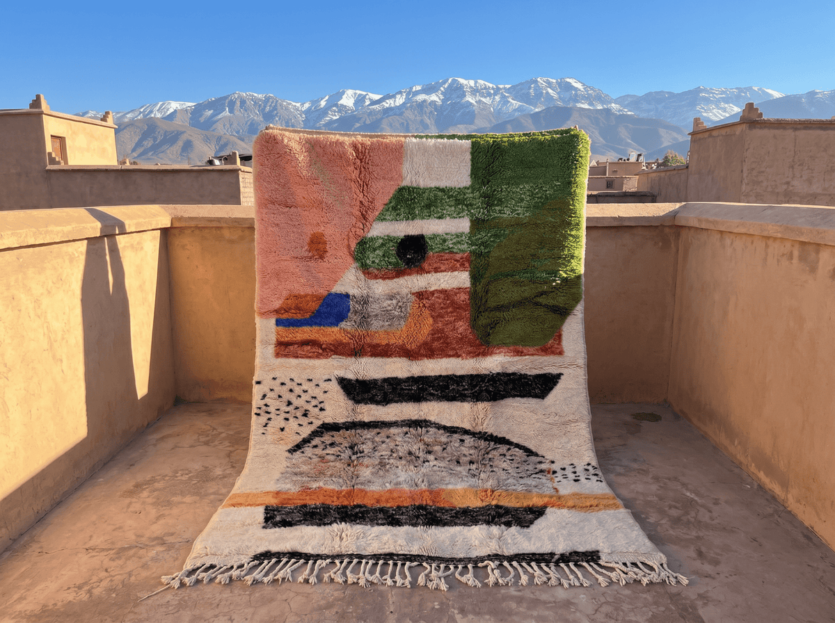 Lifestyle shot of a pink colorful Moroccan rug featuring geometric patterns and fringed edges.