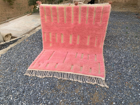 Other view of a pink Moroccan rug featuring a geometric pattern and fringe edges.