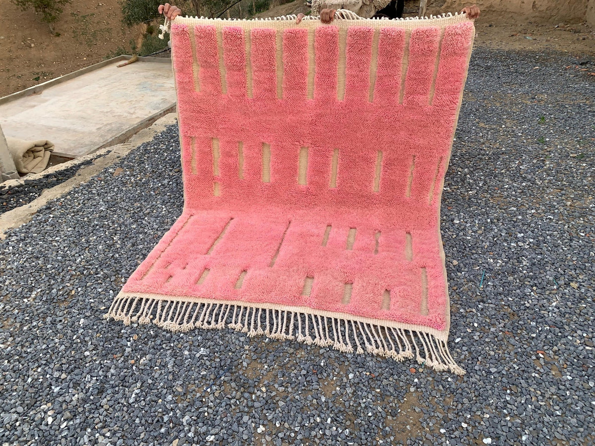 Lifestyle view of a pink Moroccan rug with geometric designs and fringe edges.