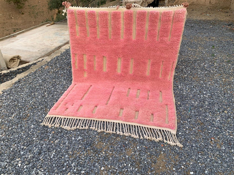Lifestyle view of a pink Moroccan rug with geometric designs and fringe edges.