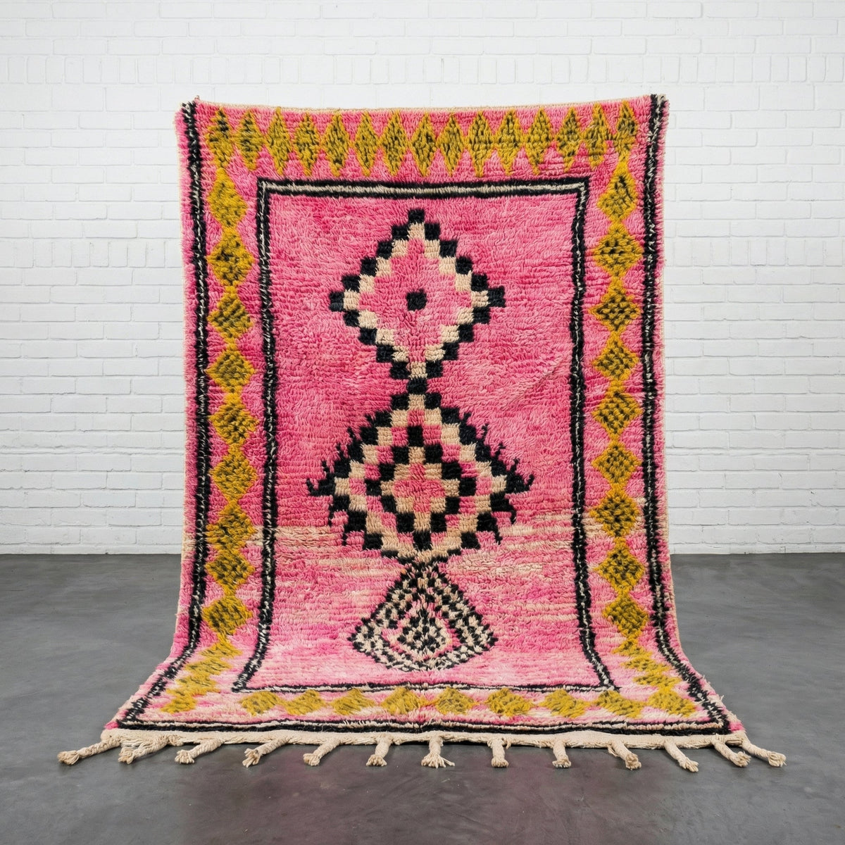 Front view of the pink tribal rug featuring geometric patterns and fringe edges.