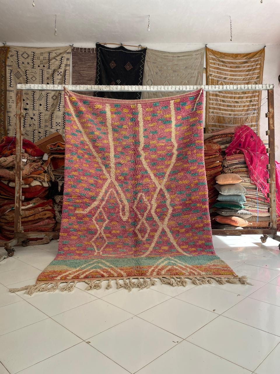 Lifestyle shot of the pink vintage Moroccan rug showcasing geometric patterns and fringe edges.