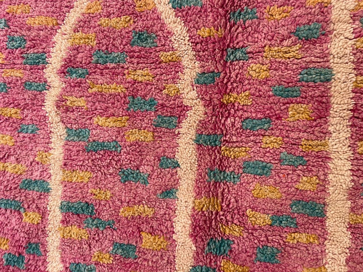 Detail close-up of the pink Moroccan rug featuring abstract designs and a soft texture.