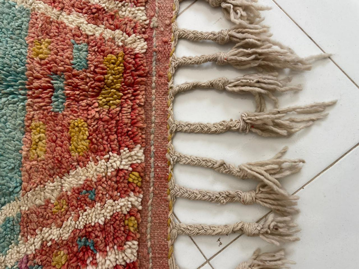 Detail close-up of the pink vintage Moroccan rug with fringed edges and intricate patterns.