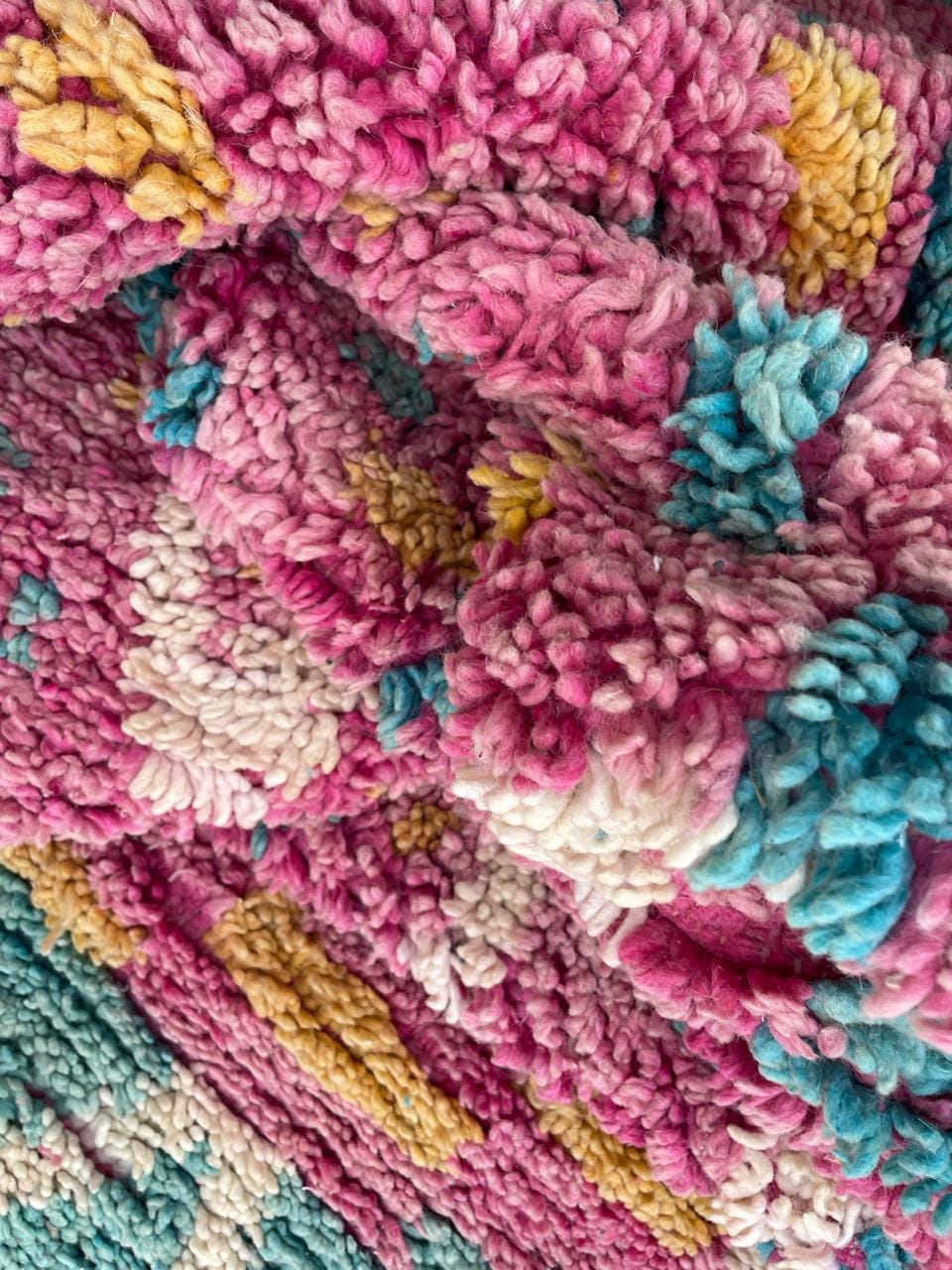 Detail close-up of the pink Moroccan rug displaying colorful motifs and a thick pile.