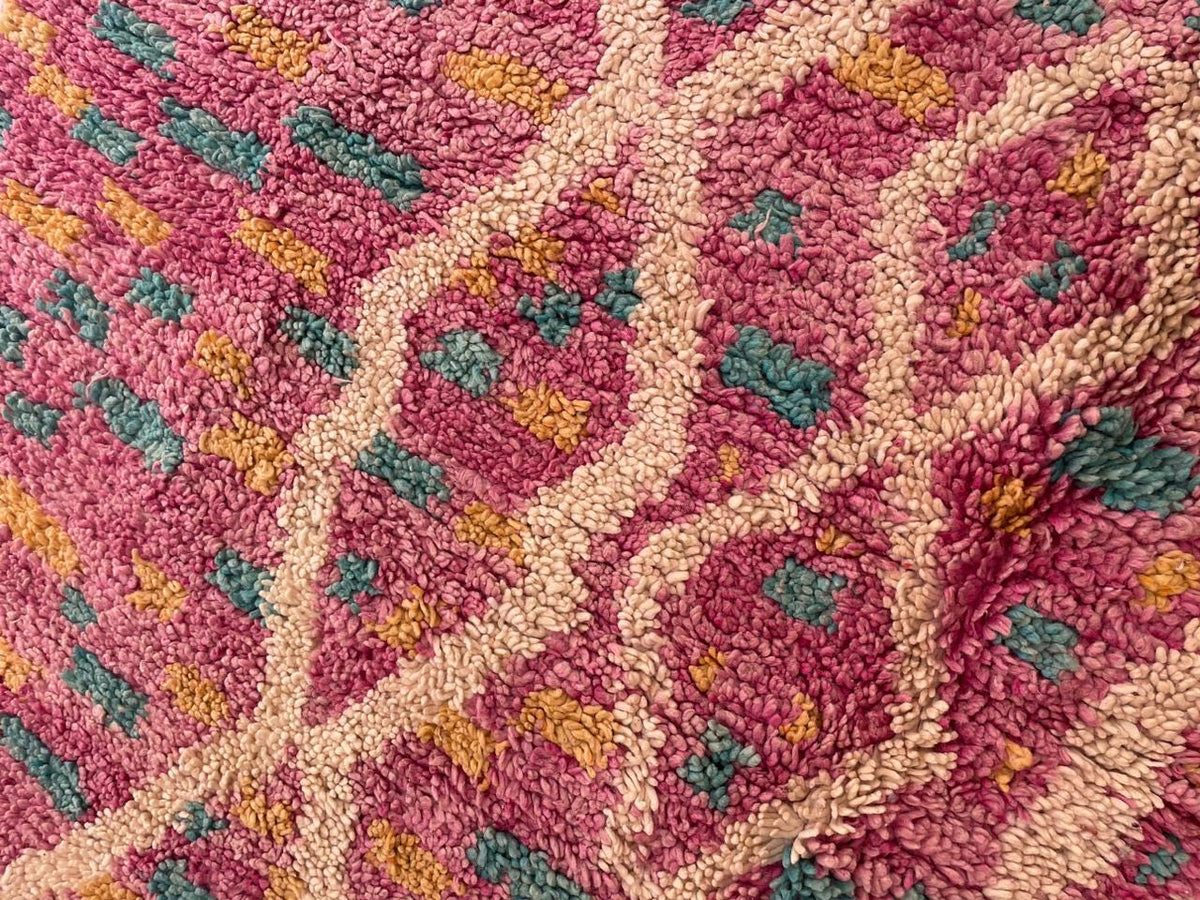 Detail close-up of the pink vintage Moroccan rug with geometric patterns and a textured surface.