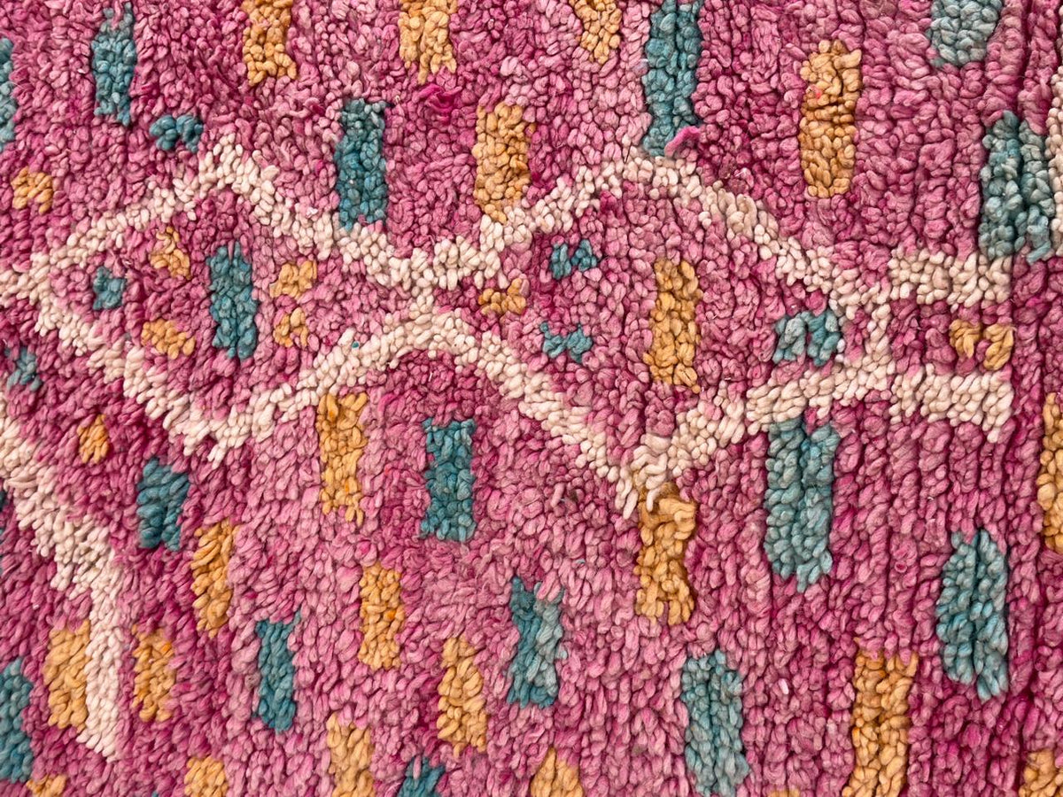 Detail close-up of the pink Moroccan rug showing geometric patterns and a textured surface.