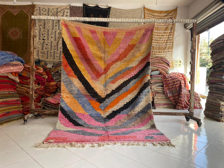 Lifestyle shot of a pink vintage Moroccan rug featuring a chevron pattern and fringe edges.