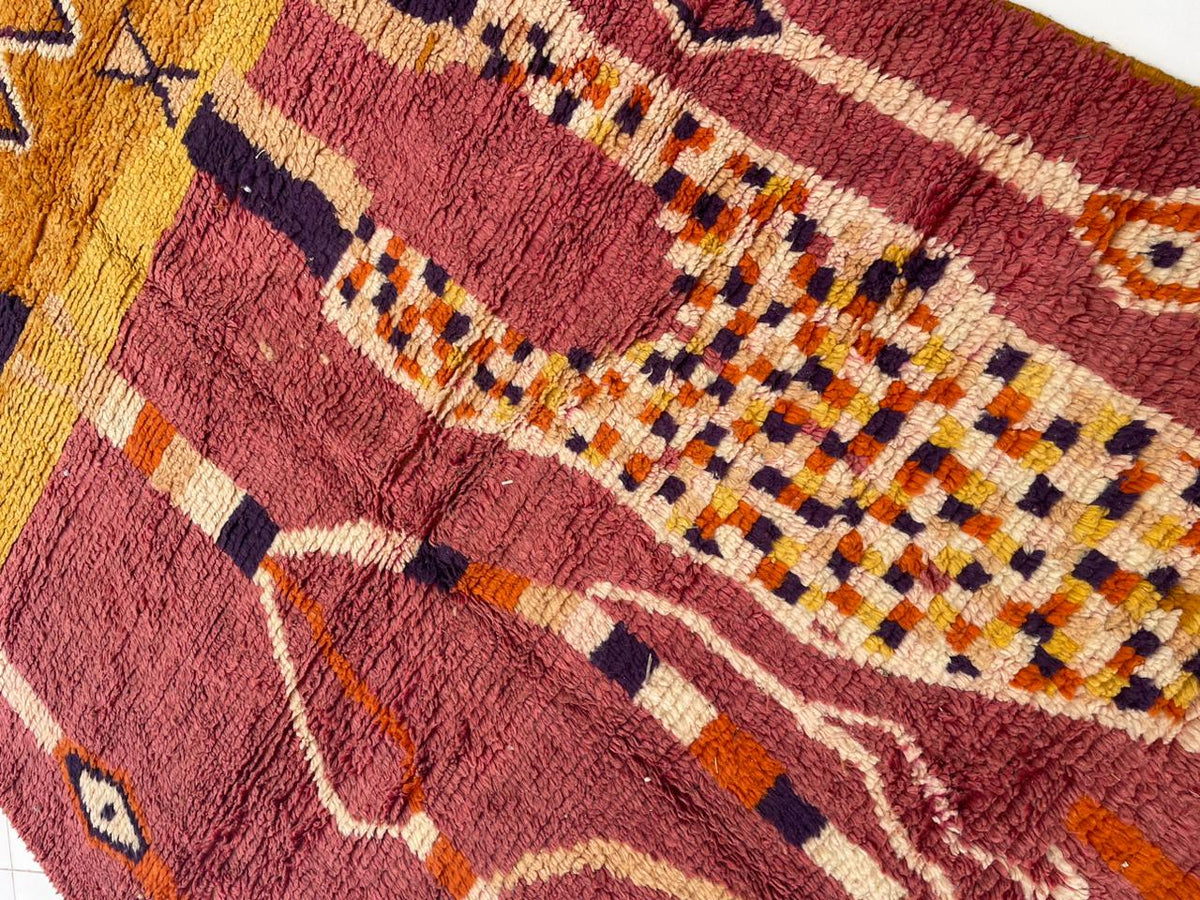 Detail close-up of a red Moroccan rug showcasing abstract designs and a handwoven texture.