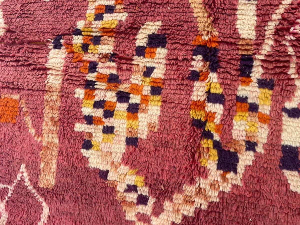 Detail close-up of a red Moroccan rug highlighting a textured surface and colorful patterns.