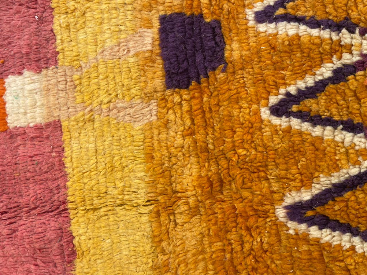 Detail close-up of a red vintage Moroccan rug featuring an abstract design and vibrant colors.