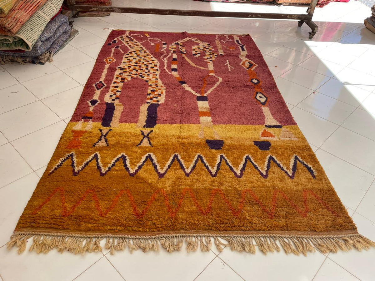Detail close-up of a red Moroccan rug with intricate designs and fringe edges.
