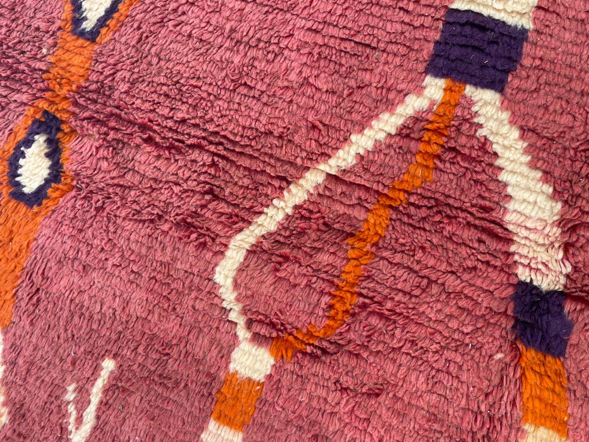 Detail close-up of a red vintage Moroccan rug with plush fibers and curved lines.