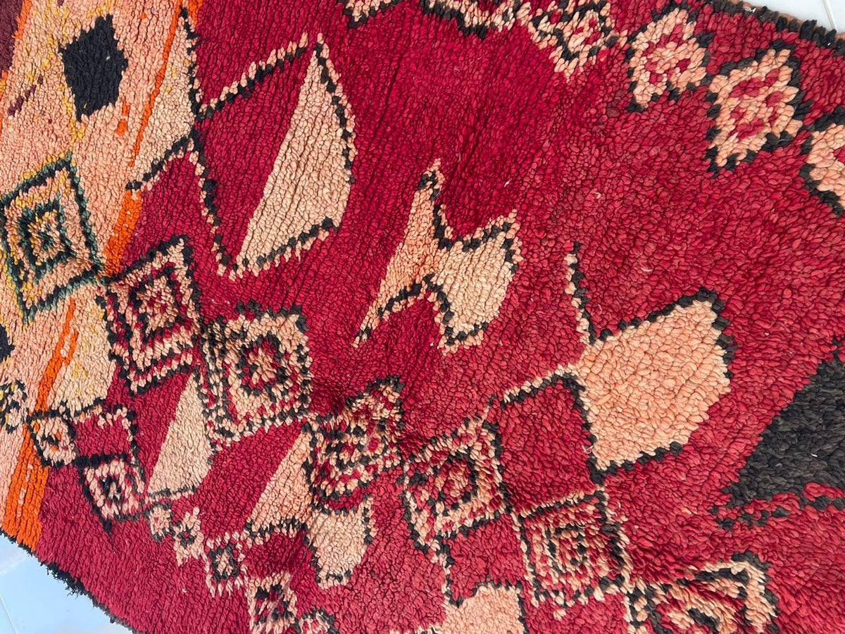 Detail shot showcasing abstract shapes and colorful patterns on a red vintage Moroccan rug.