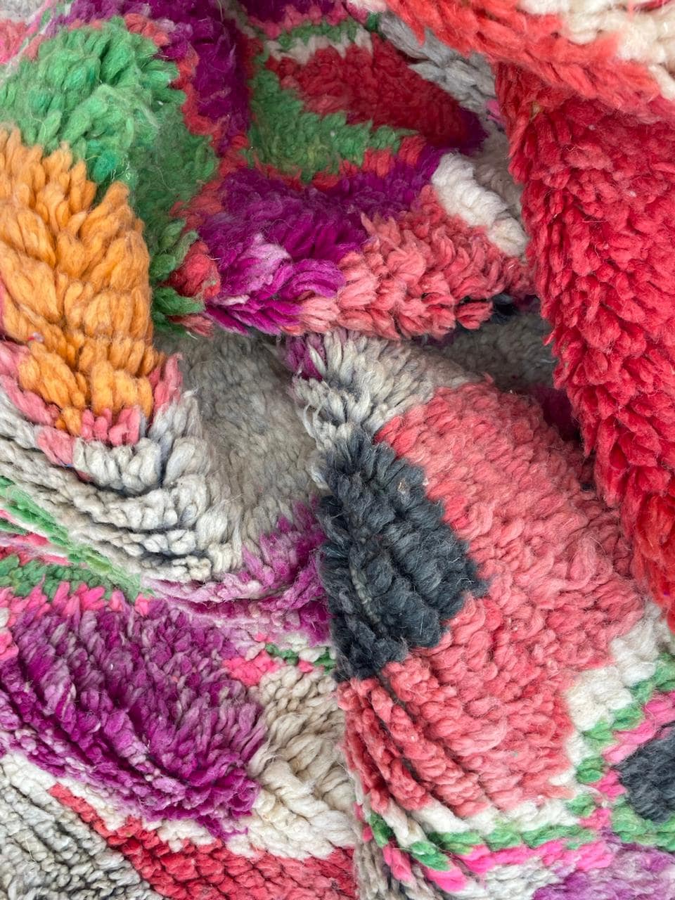 Detail shot of a vintage Moroccan rug displaying colorful patterns with red, orange, and purple.