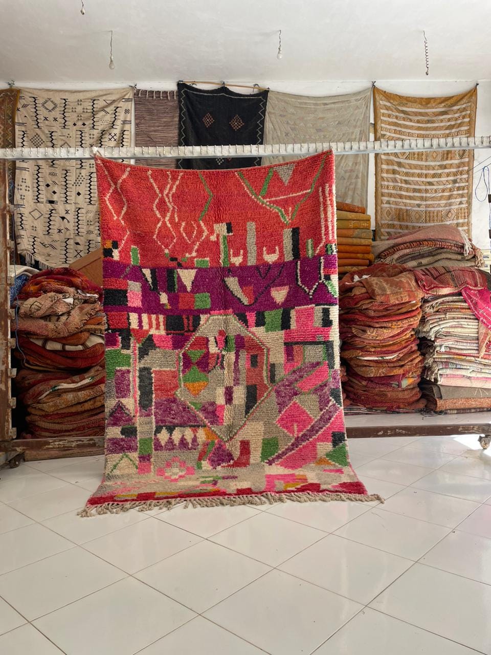 Lifestyle shot of a red vintage Moroccan rug featuring tribal patterns and fringe edges.