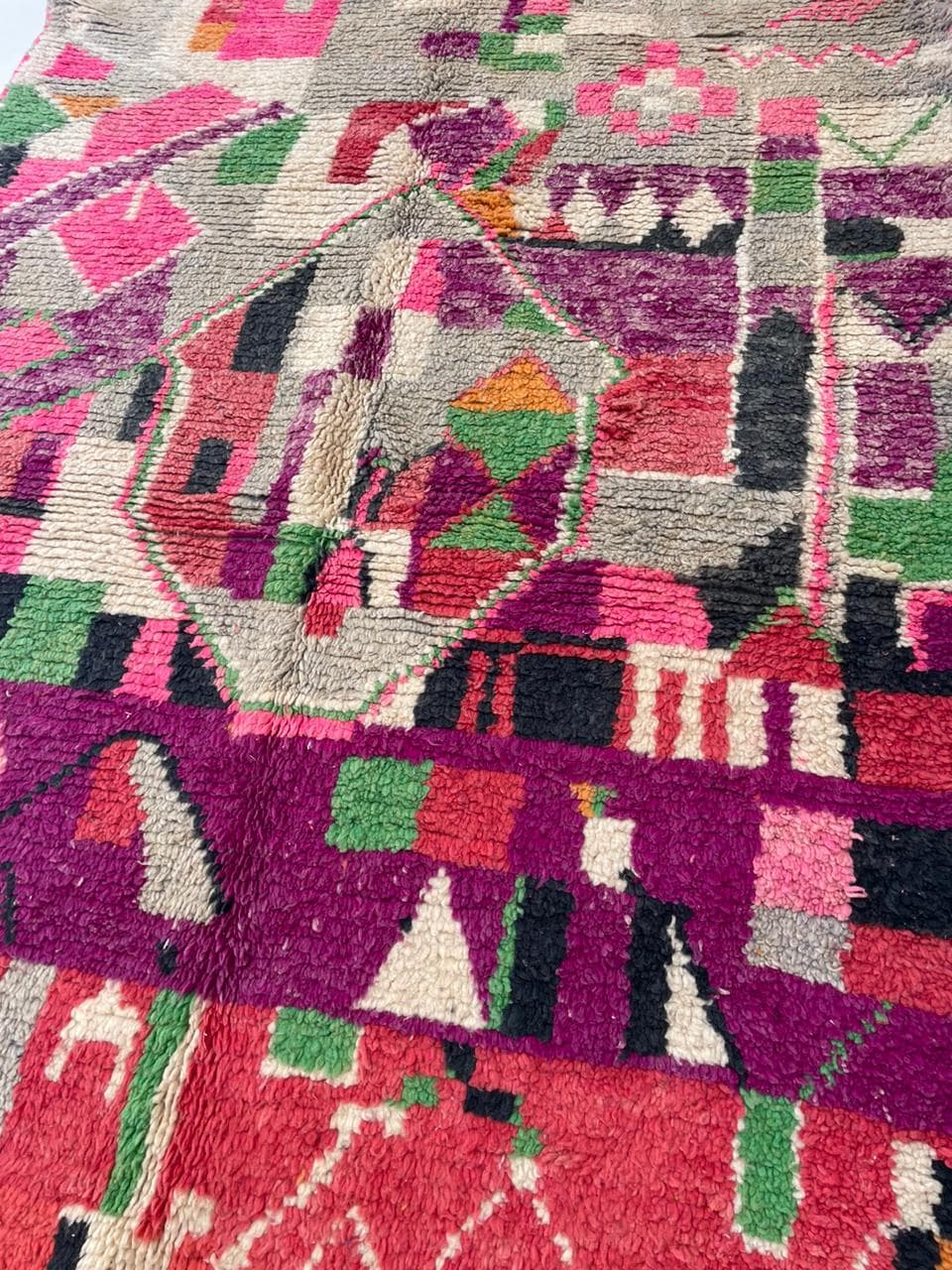 Close-up detail of the texture on a red vintage Moroccan rug with tribal patterns.