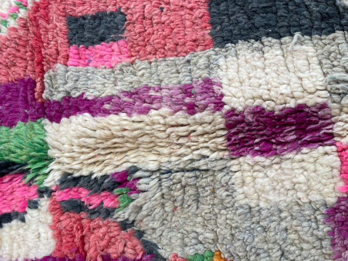 Detail view of a vintage Moroccan rug showcasing colorful tribal patterns in purple and pink.