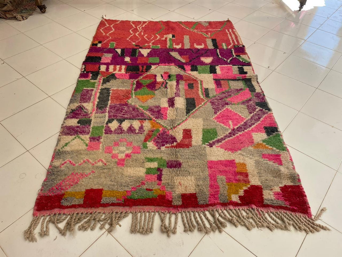 Top view of a red vintage Moroccan rug showcasing tribal patterns with colors of red, pink, and beige.