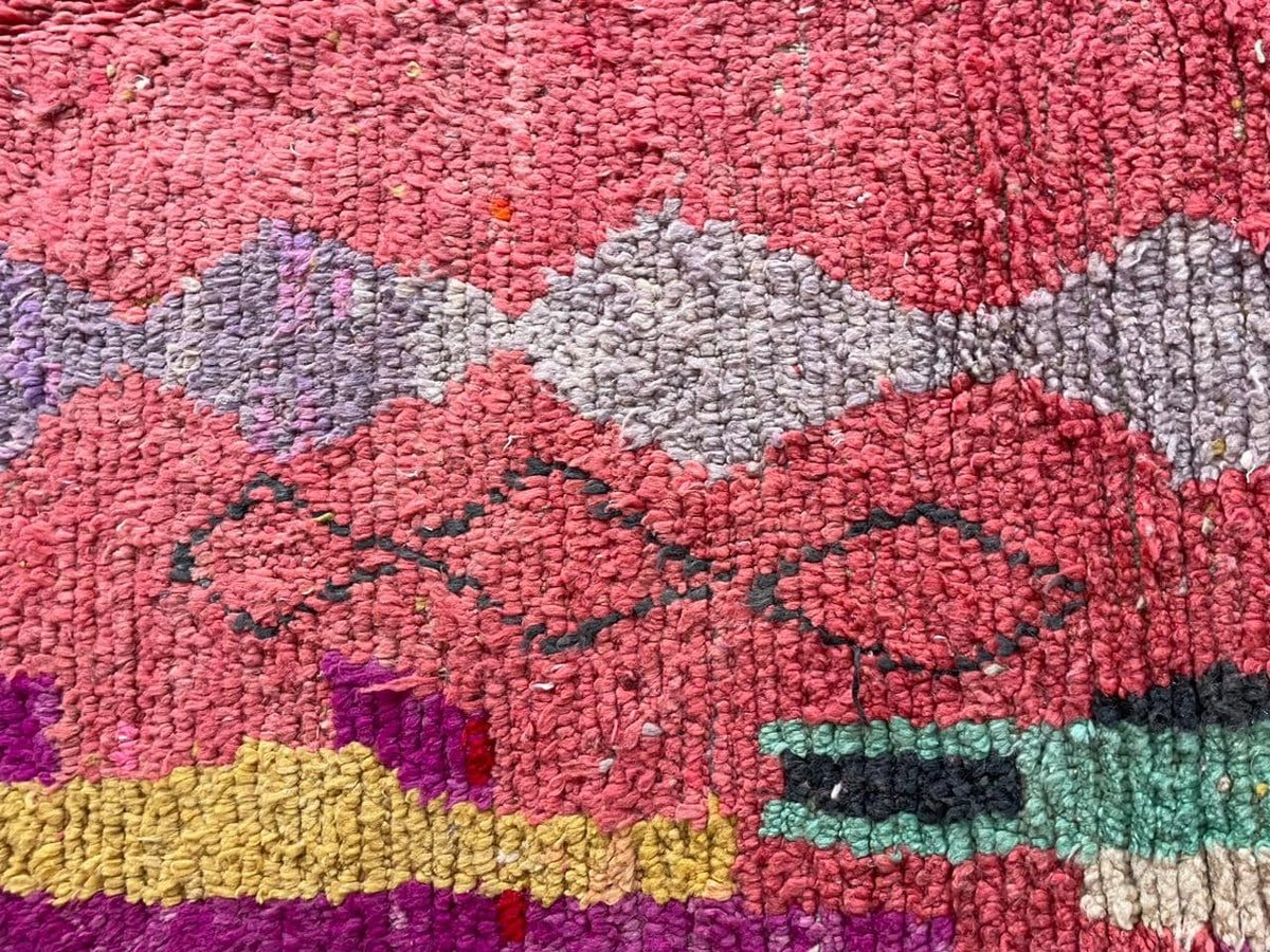 Detail view of the vintage rug showing tribal patterns with a mix of colors.