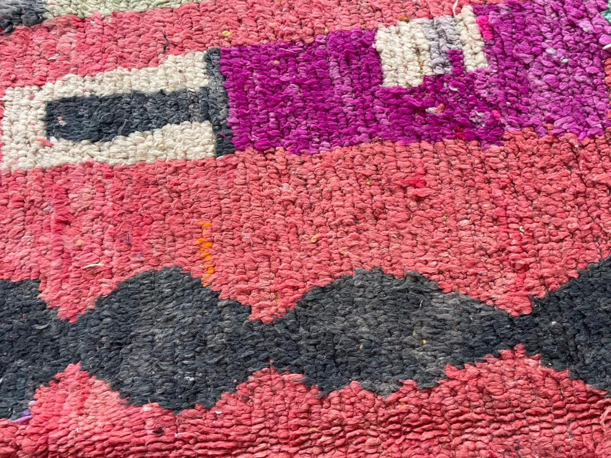 Detail view of the vintage Moroccan rug featuring tribal patterns in red and black.