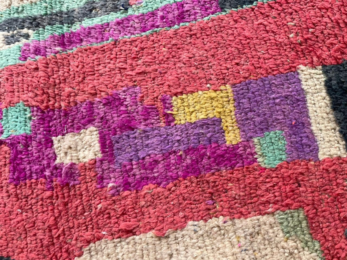 Detail close-up of the vintage rug displaying tribal patterns in vibrant colors.
