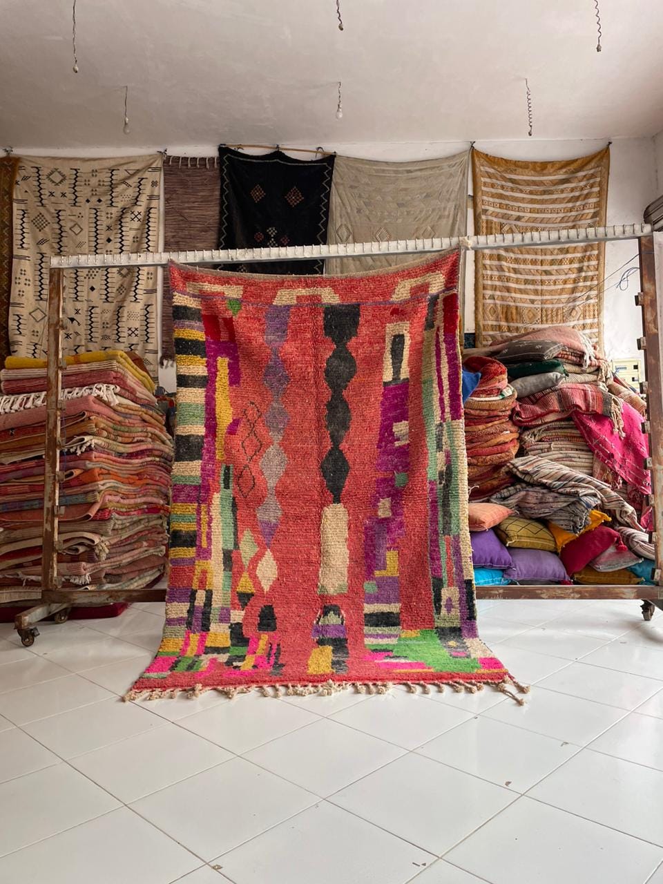 Lifestyle shot of a red vintage Moroccan rug with tribal patterns and fringed edges.