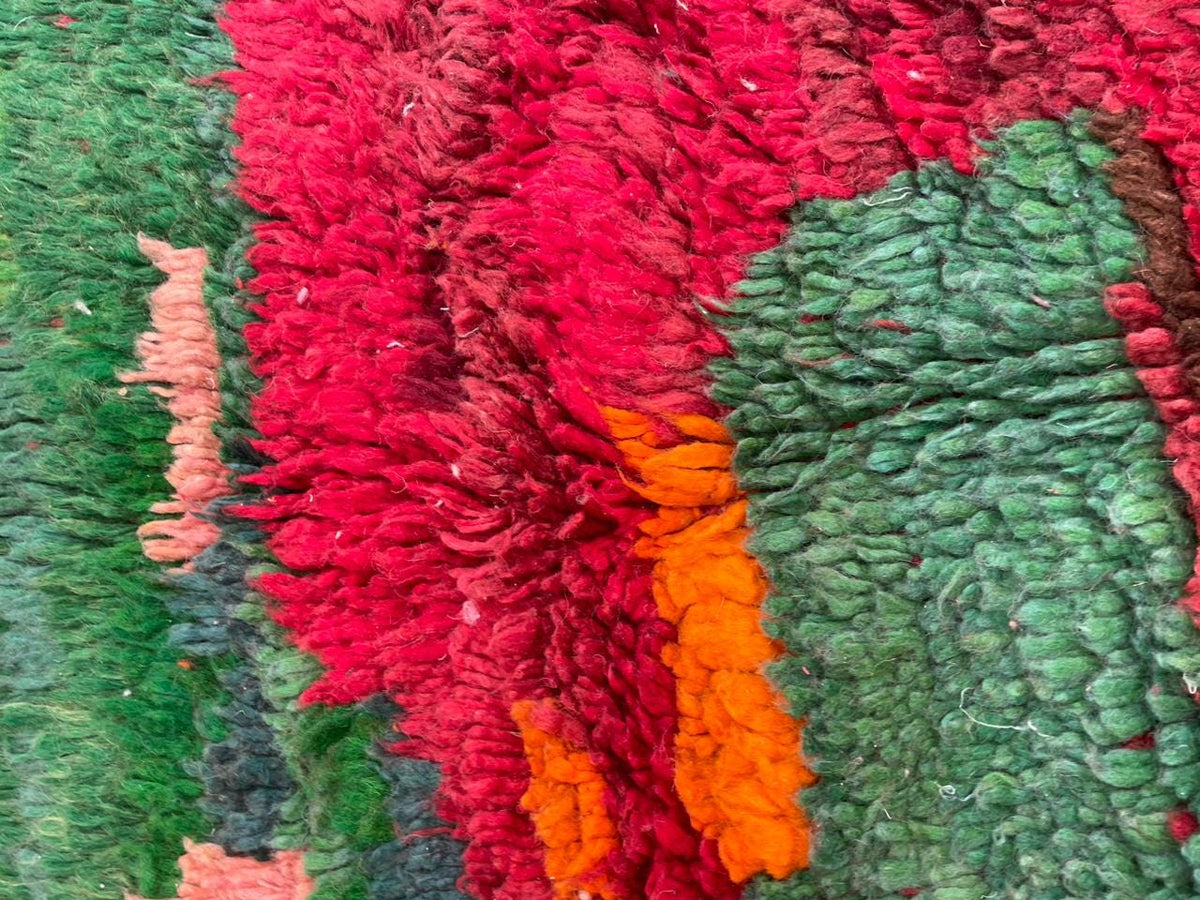 Detail close-up of the red vintage Moroccan rug showcasing tribal patterns and colors.