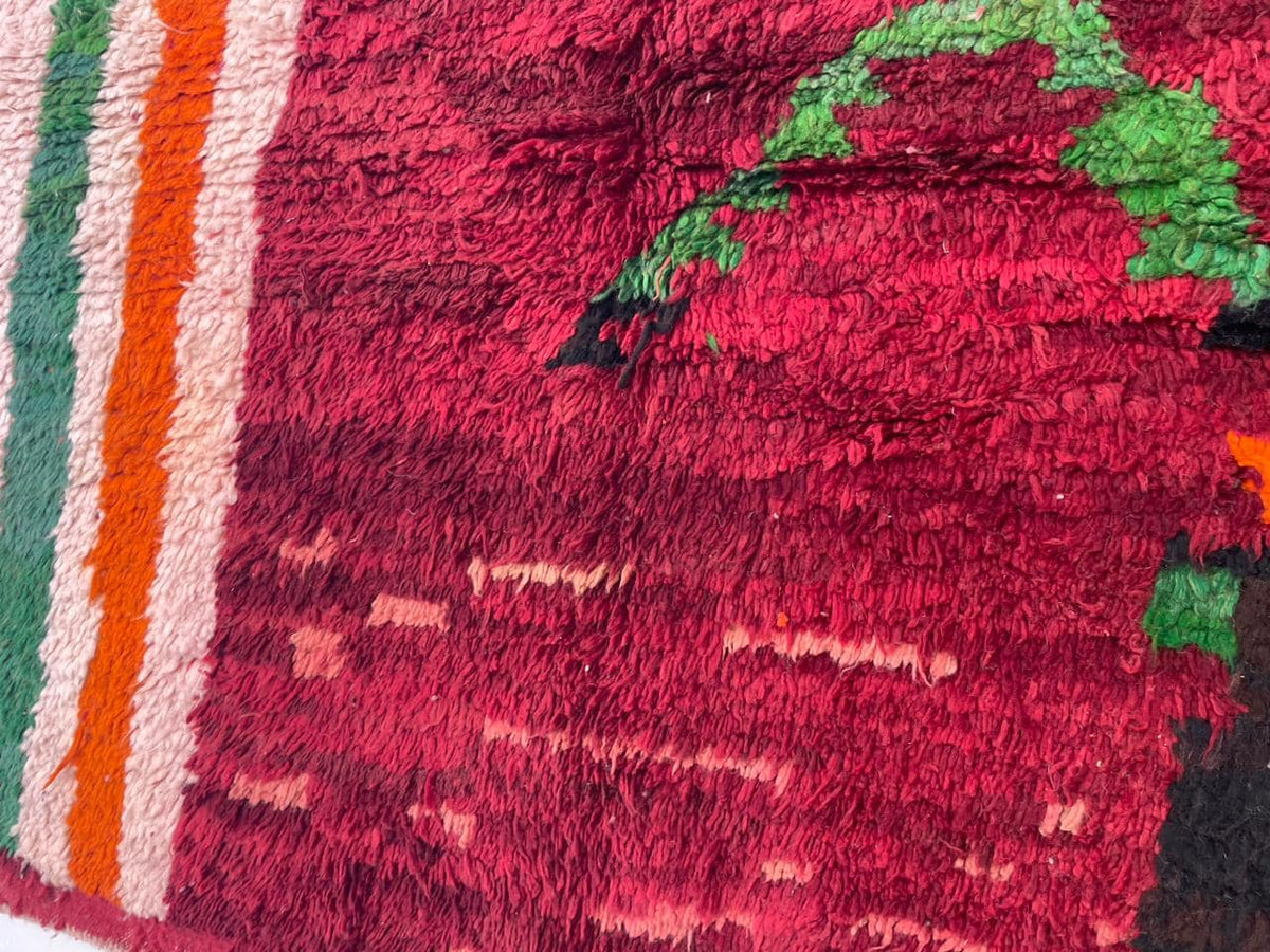 Detail close-up of the red vintage Moroccan rug showcasing tribal patterns and texture.
