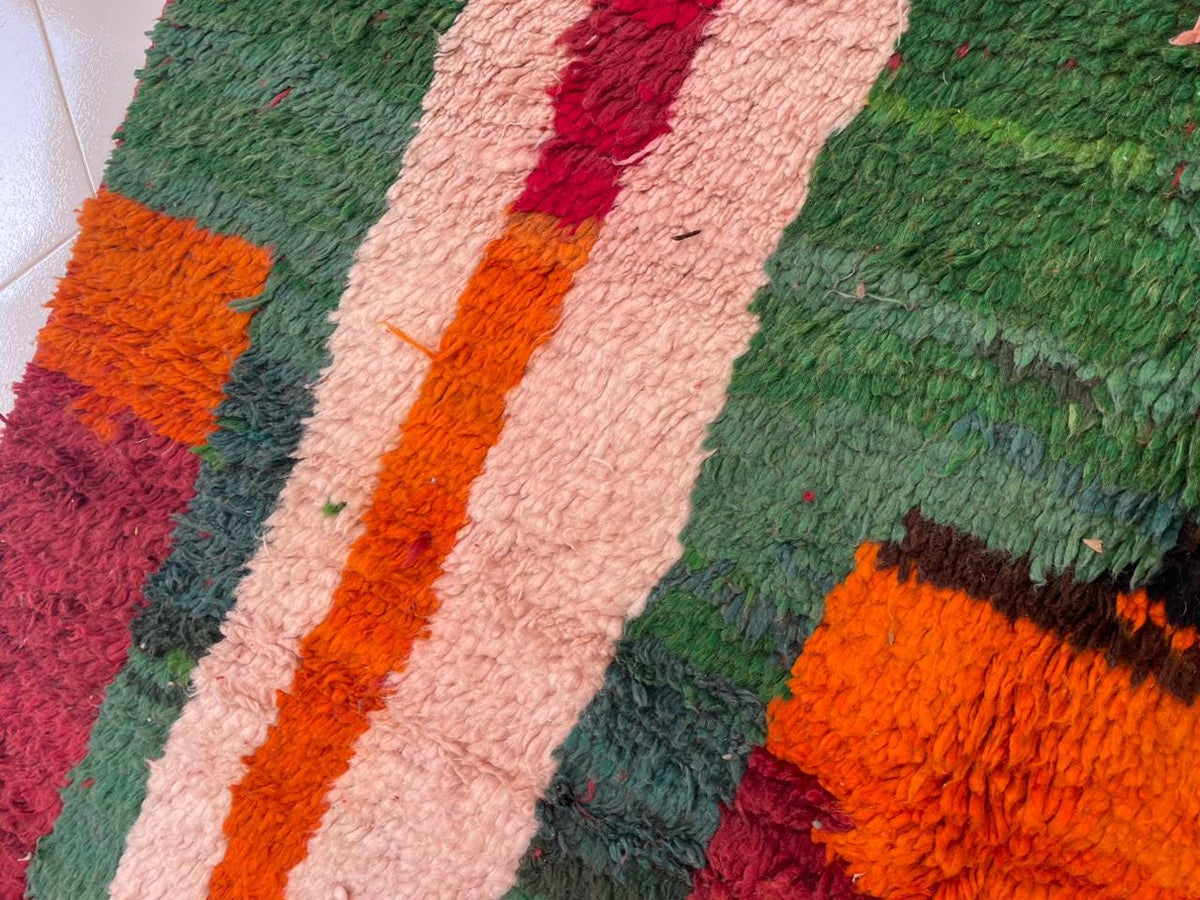 Detail close-up of the red vintage Moroccan rug featuring tribal patterns and vibrant hues.