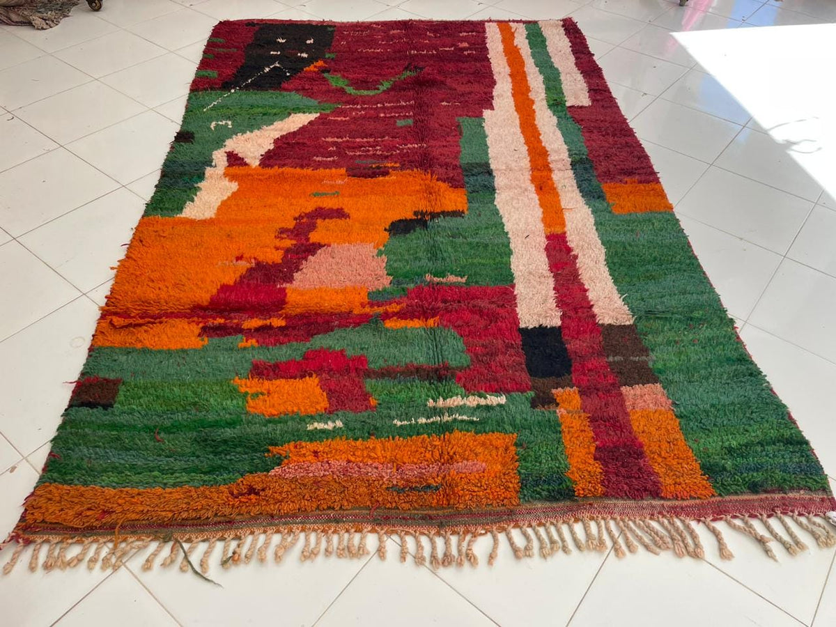 Front view of a red vintage Moroccan rug featuring tribal designs and vibrant colors.