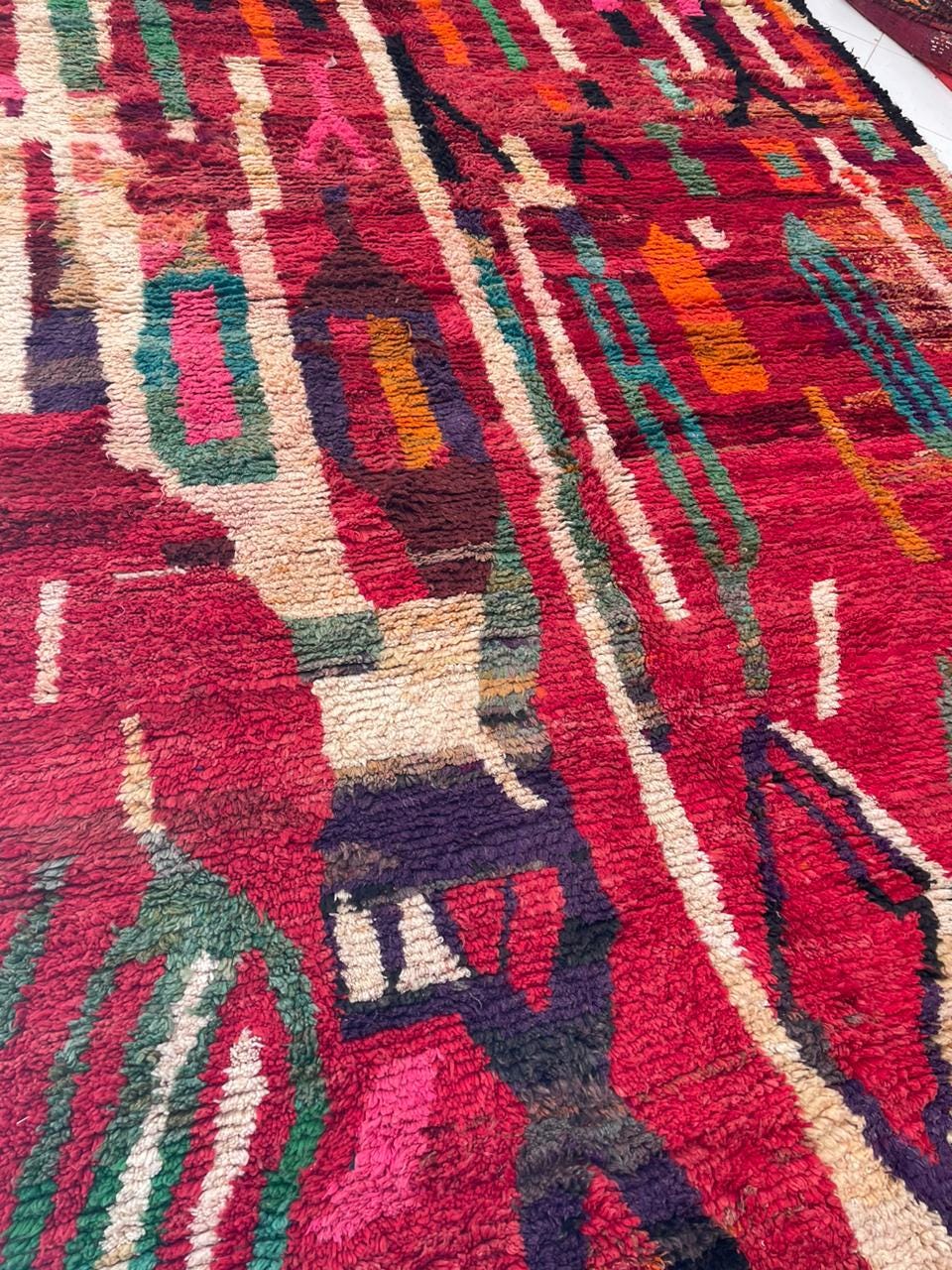 Close-up detail of a red vintage Moroccan rug showcasing tribal designs and texture.