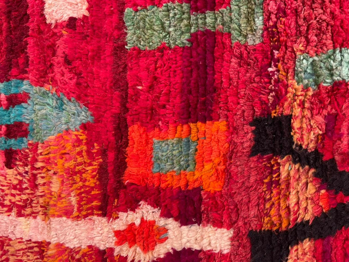 Close-up detail of a red vintage Moroccan rug with tribal patterns and vibrant colors.