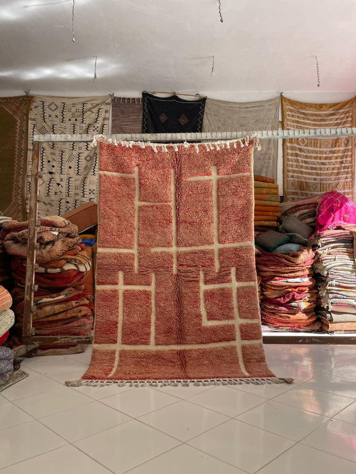 Lifestyle shot of a red vintage Moroccan rug with geometric patterns on a natural background.