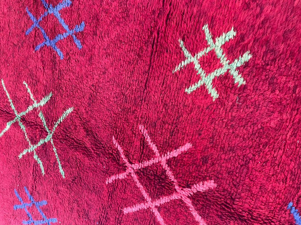 Close-up detail of a red vintage Moroccan rug highlighting tribal patterns and a soft texture.