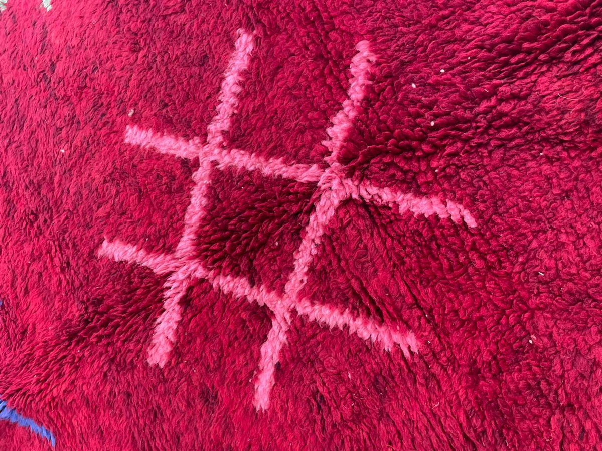Detail shot of a red tribal rug featuring a geometric pattern and a soft texture.