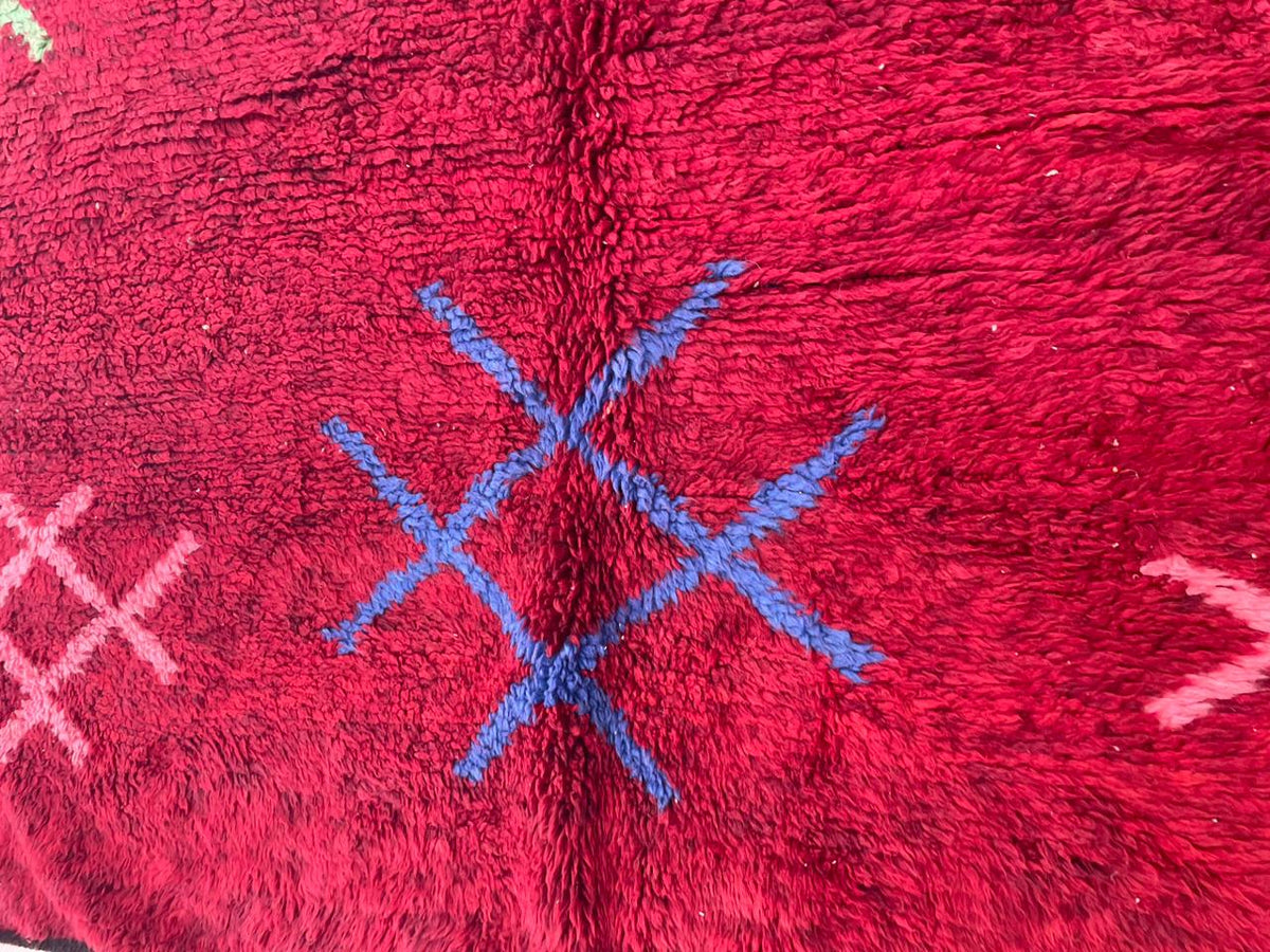 Close-up detail of a red vintage Moroccan rug with geometric patterns and a soft texture.