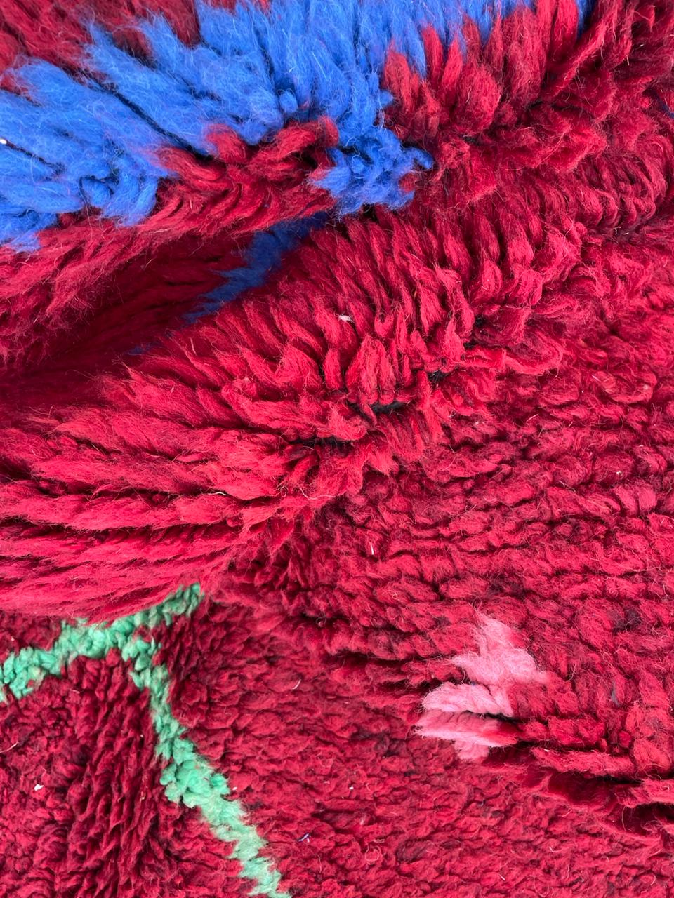 Detail shot of a red tribal rug with an abstract design and thick pile.