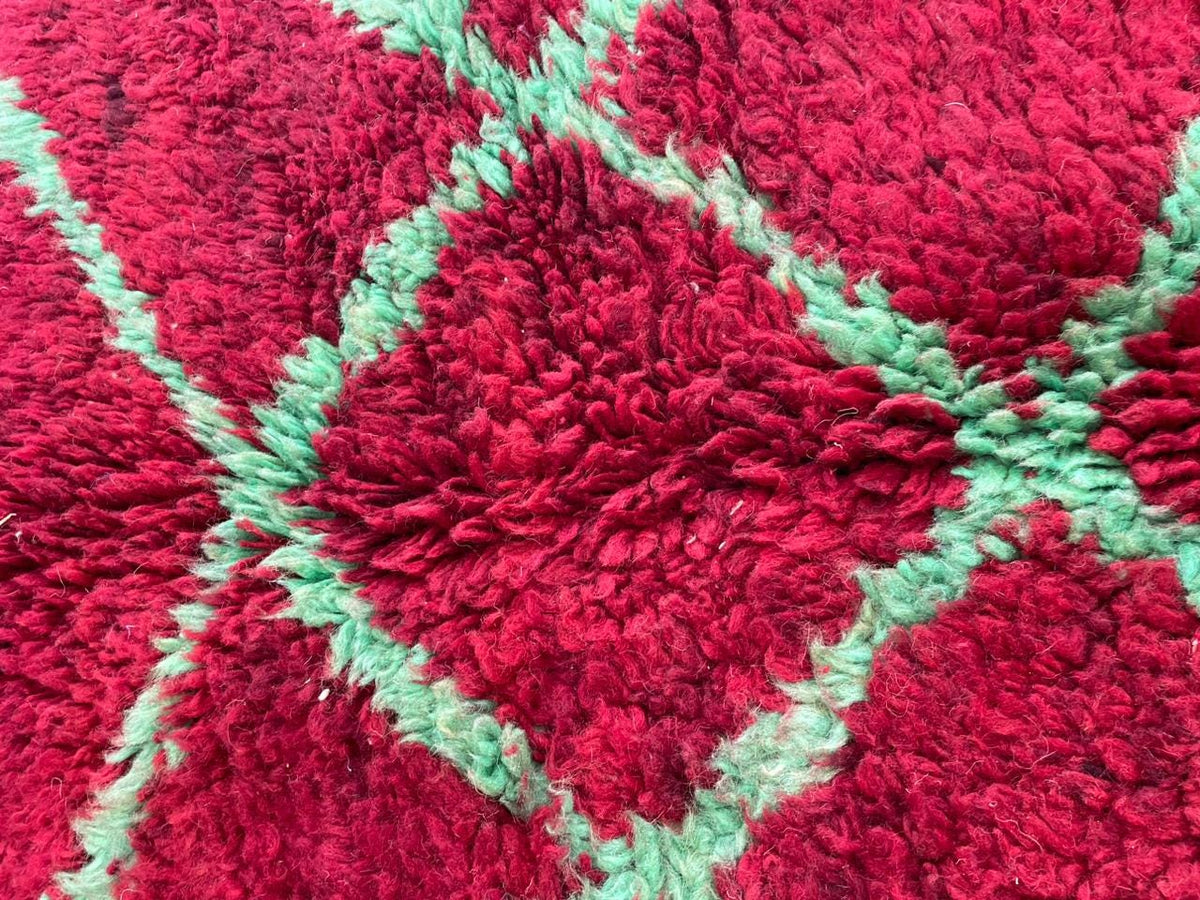Detail shot of a red tribal rug with a diamond pattern and fluffy texture.