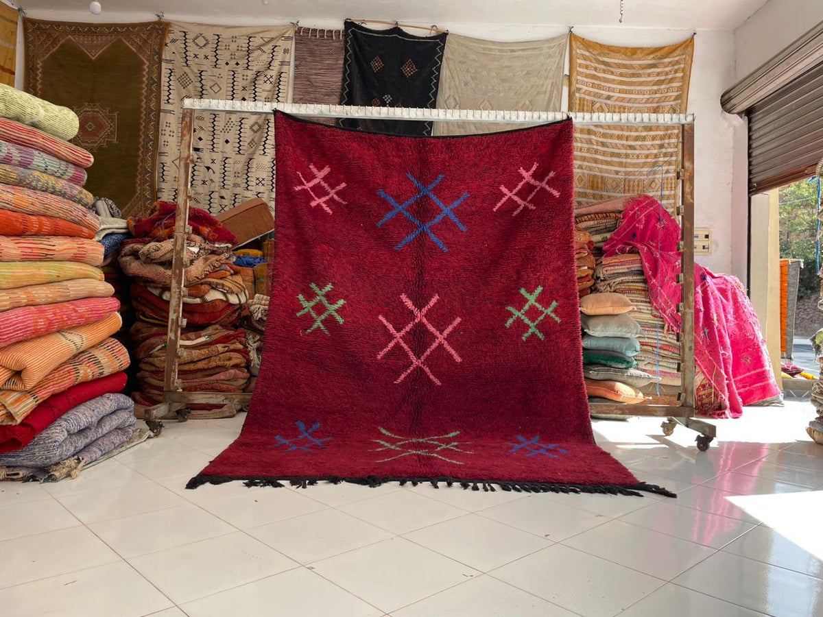Lifestyle shot of a red vintage Moroccan rug featuring tribal patterns and a large size.