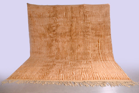 Lifestyle shot of a beige and brown Moroccan Mrirt rug with a textured surface.