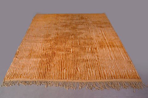 Top view of an orange and beige Moroccan Mrirt rug featuring soft texture and fringed edges.