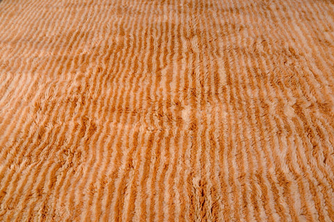 Detail close-up of an orange and beige Moroccan Mrirt rug featuring a textured surface and striped pattern.