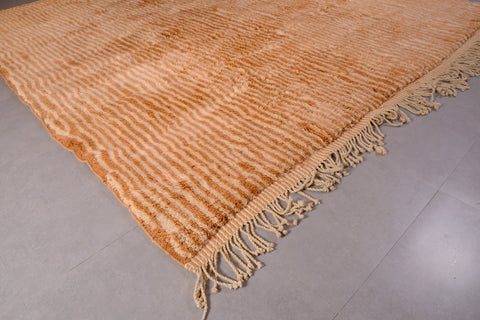 Detail close-up of an orange and beige Moroccan Mrirt rug showing a smooth surface and fringe edges.