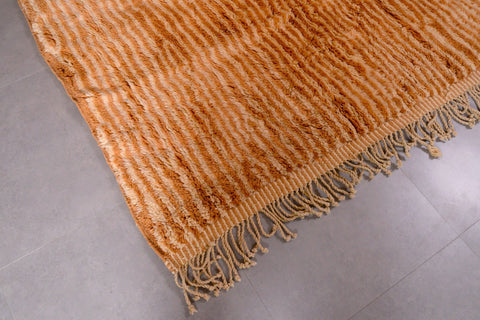 Detail close-up of an orange and beige Moroccan Mrirt rug showing thick pile and fringed edges.
